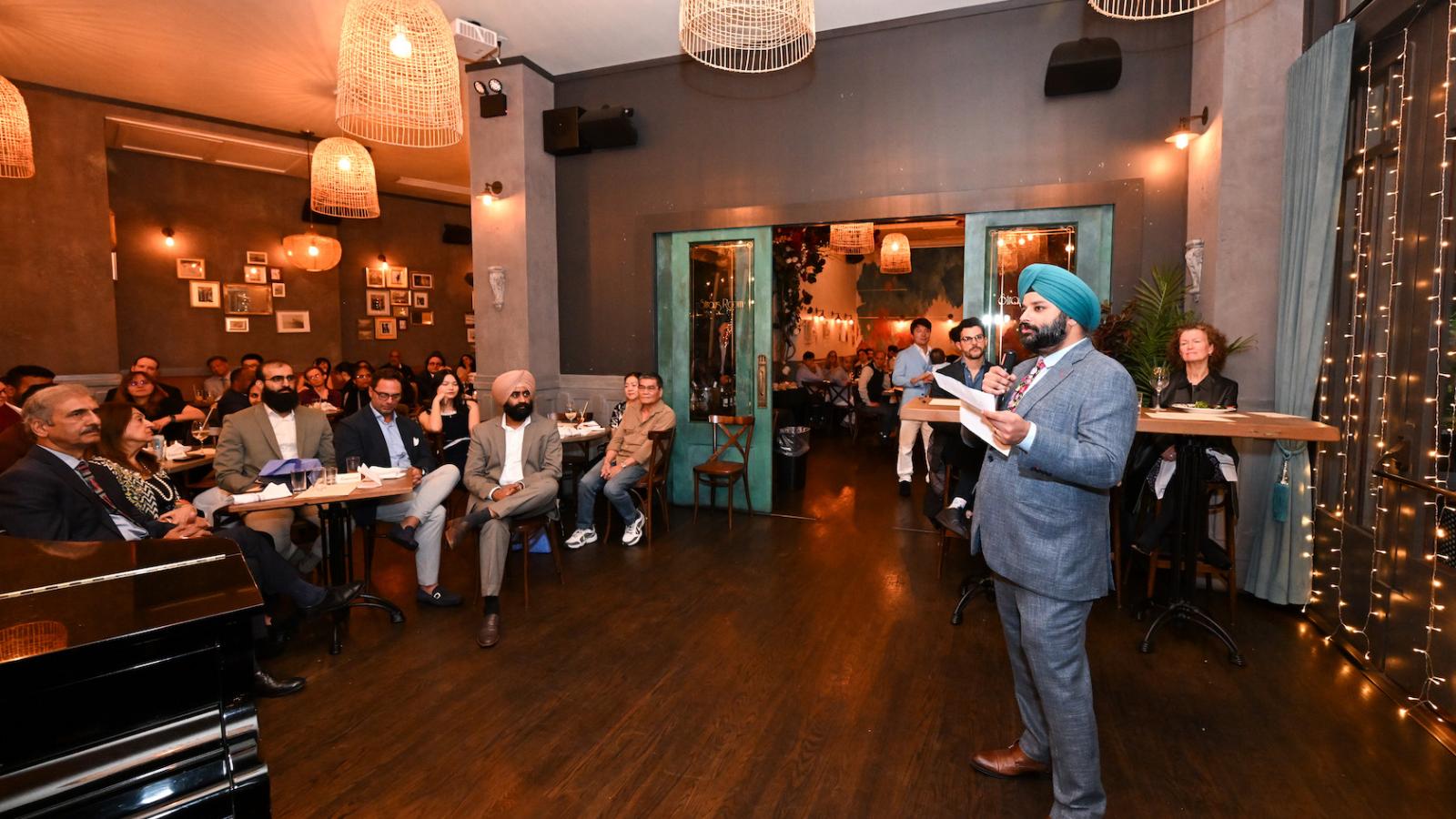 Man with microphone speaks to group in restaurant