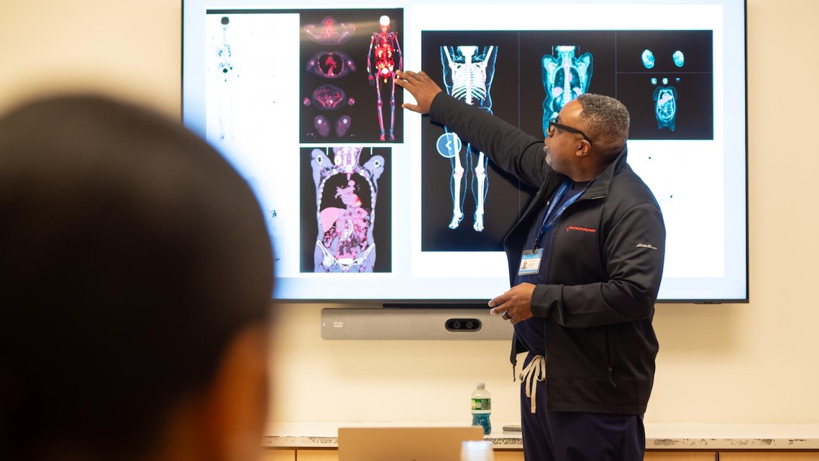 Man points to screen with radiology images