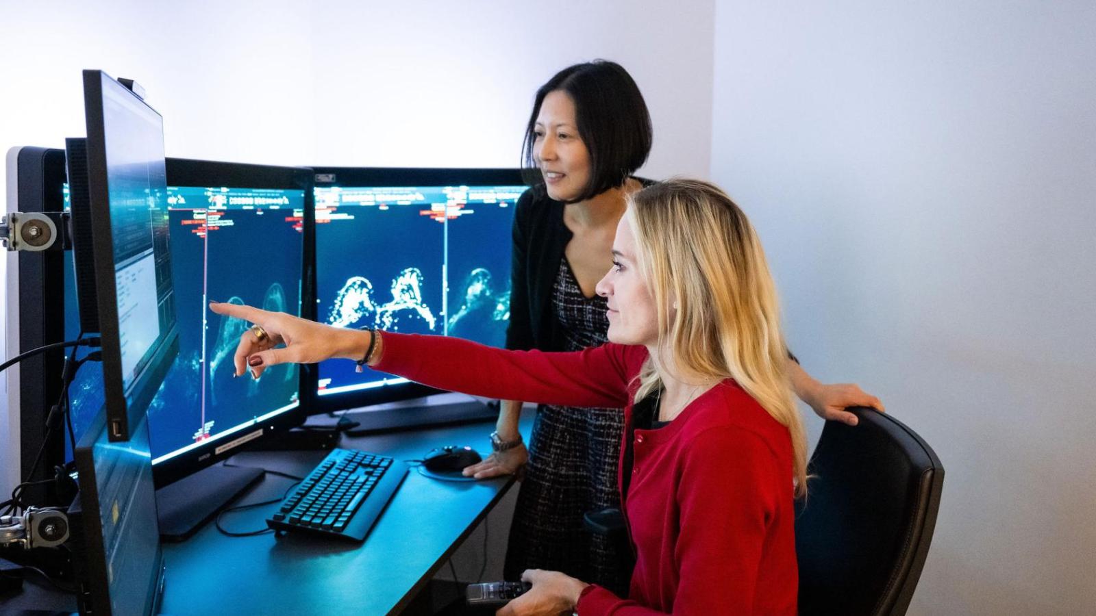 Two female radiologists look at images on screen