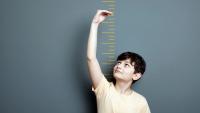 Boy measuring his height on ruler