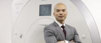 Dr. Tony Wong stands in front of an MRI scanner.